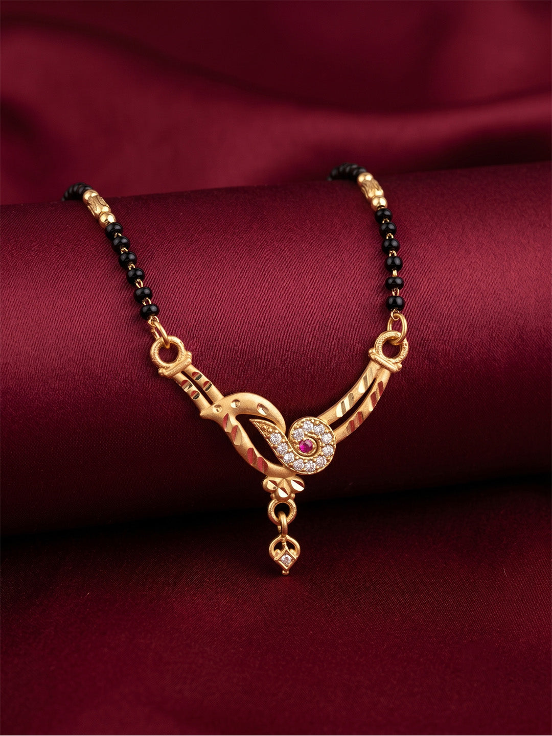 lfariya jewellery luxury gold plated black bead mangalsutra with an American Diamond square pendant and ruby red stone, styled on a white ceramic plate.