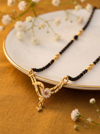lfariya jewellery designer gold and black beaded mangalsutra with a square pendant, red gemstone centerpiece and American Diamond border on a white ceramic display.