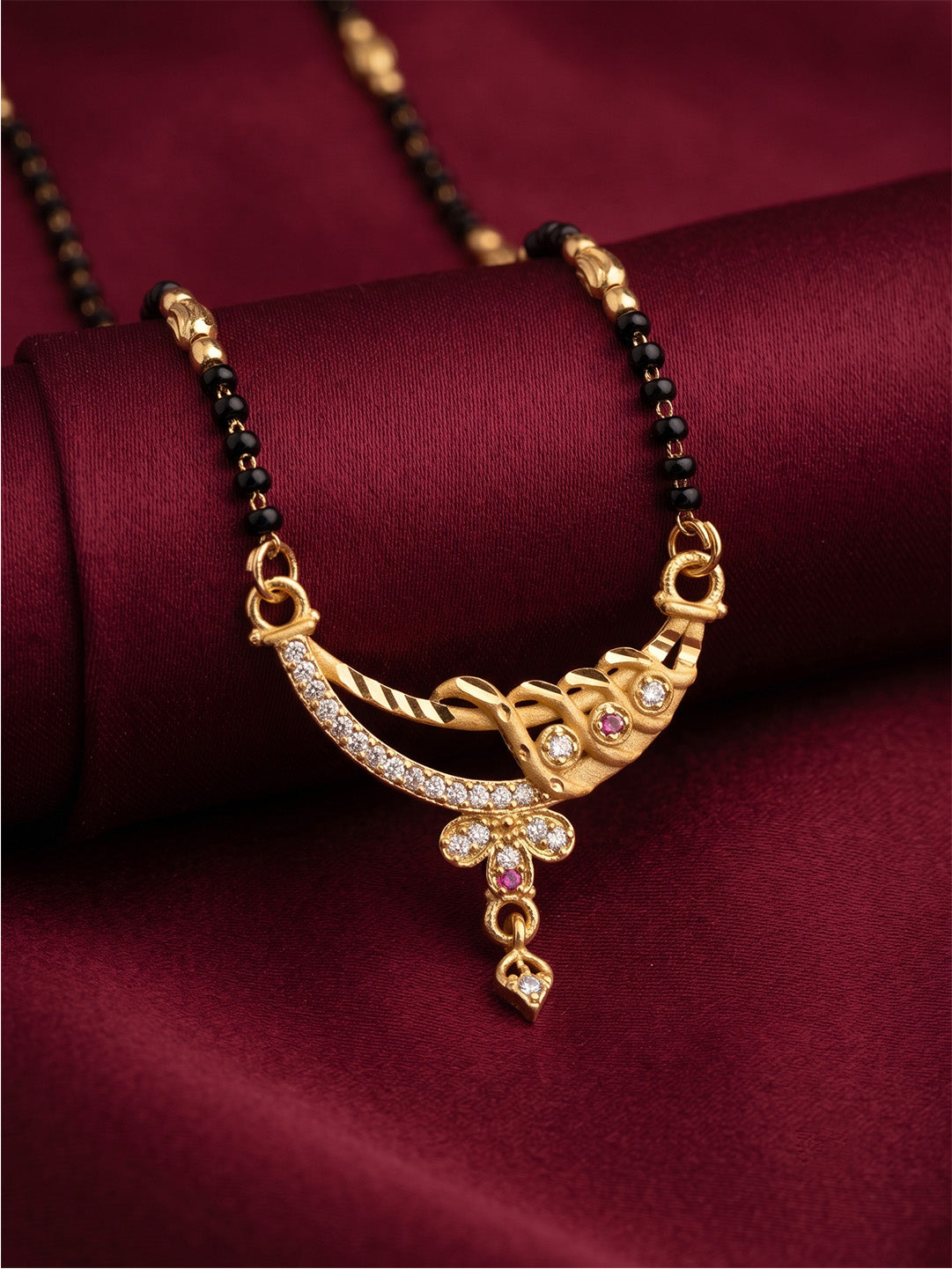 lfariya jewellery gold plated mangalsutra necklace with black beads, square American Diamond pendant and red center stone, displayed on a premium white ceramic plate with gold trim.