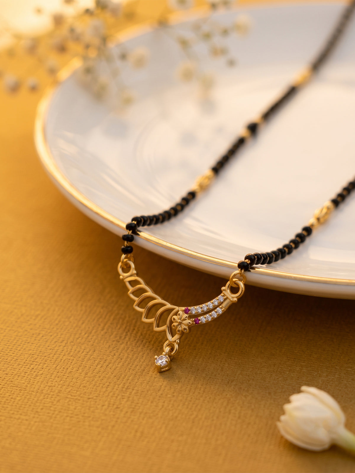 lfariya jewellery luxury mangalsutra necklace with an elegant square gemstone pendant, premium gold plated finish, traditional black bead chain and timeless Indian jewelry styling on a decorative display plate