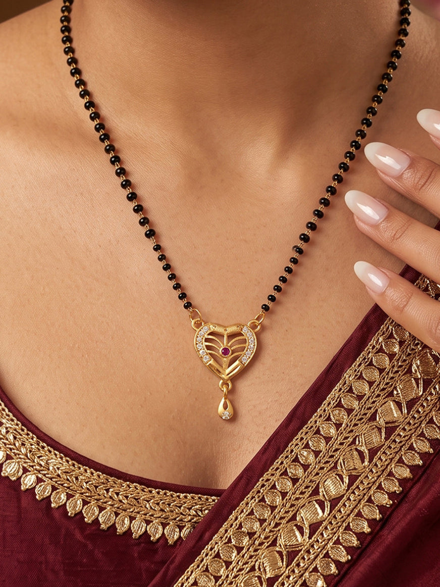 Beautiful heart-shaped gold plated mangalsutra pendant with leaf pattern, CZ stones, black beads chain and elegant drop charm for women, ideal for festivals, weddings and daily wear.