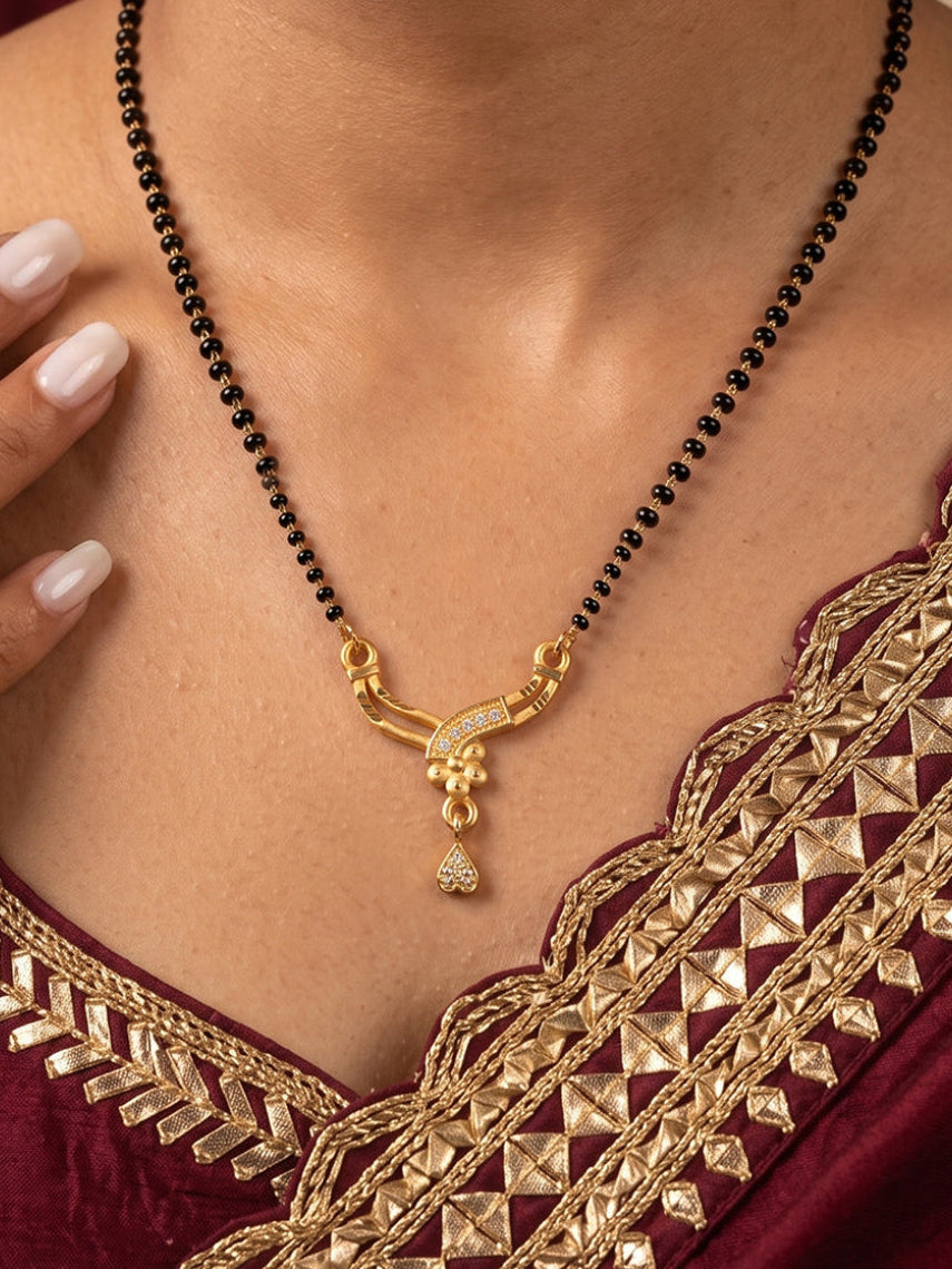Traditional curved drop mangalsutra with black beads chain, CZ-studded gold pendant and heart-shaped drop by Lfariya Jewellery.